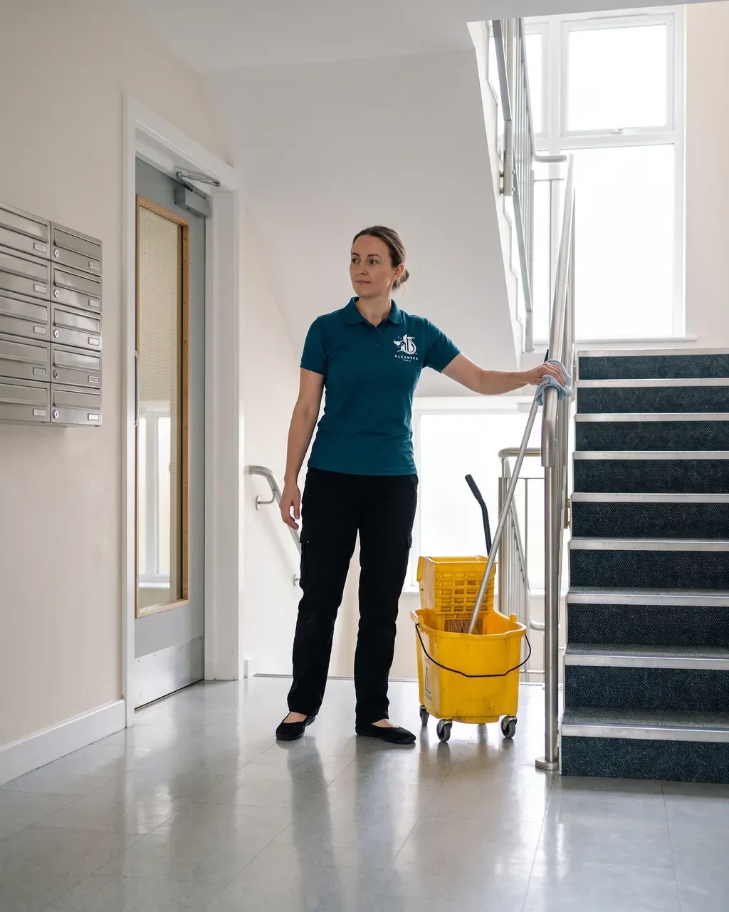 Commercial Cleaners Bournemouth cleaner wiping down the handrail in the communal stairwell of a Bournemouth block of flats